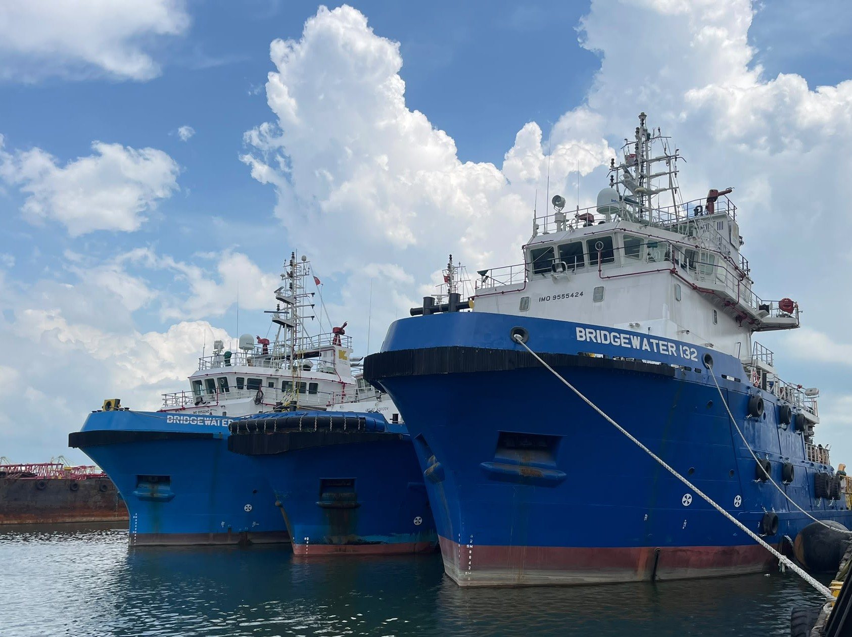 Three blue offshore support vessels, including Bridgewater 132, moored alongside a quay